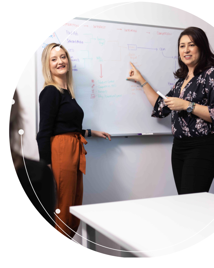 Jess and Silvia Showing Plans on a Whiteboard-1